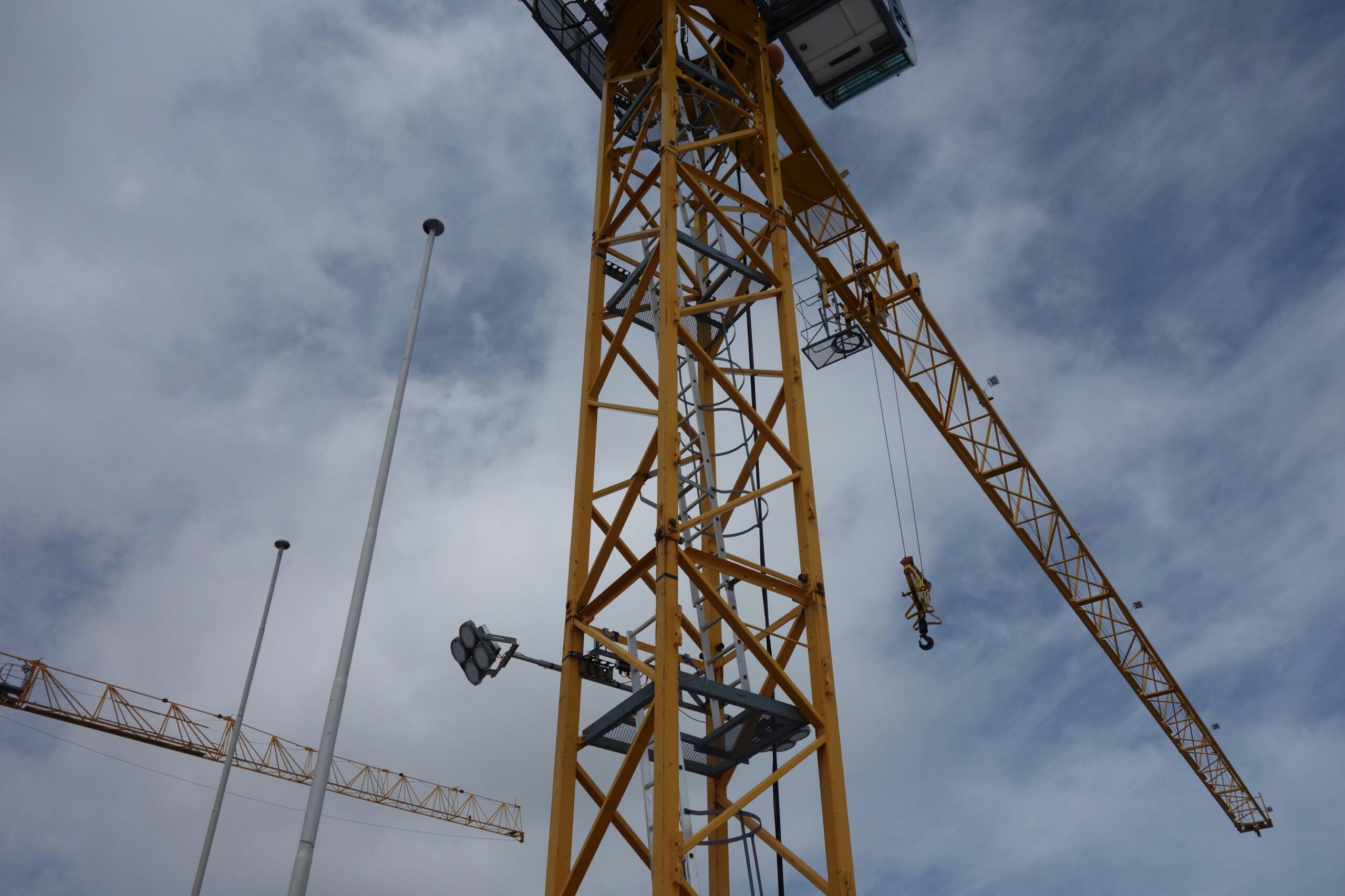 A towering construction crane set against a backdrop of a cloudy sky.