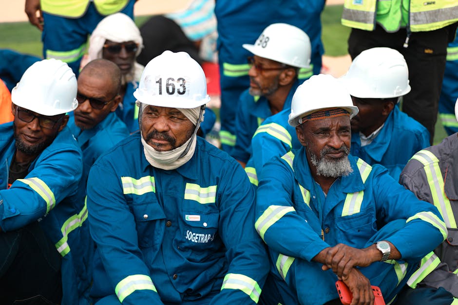 Construction workers in blue uniforms and white helmets during a break outdoors.